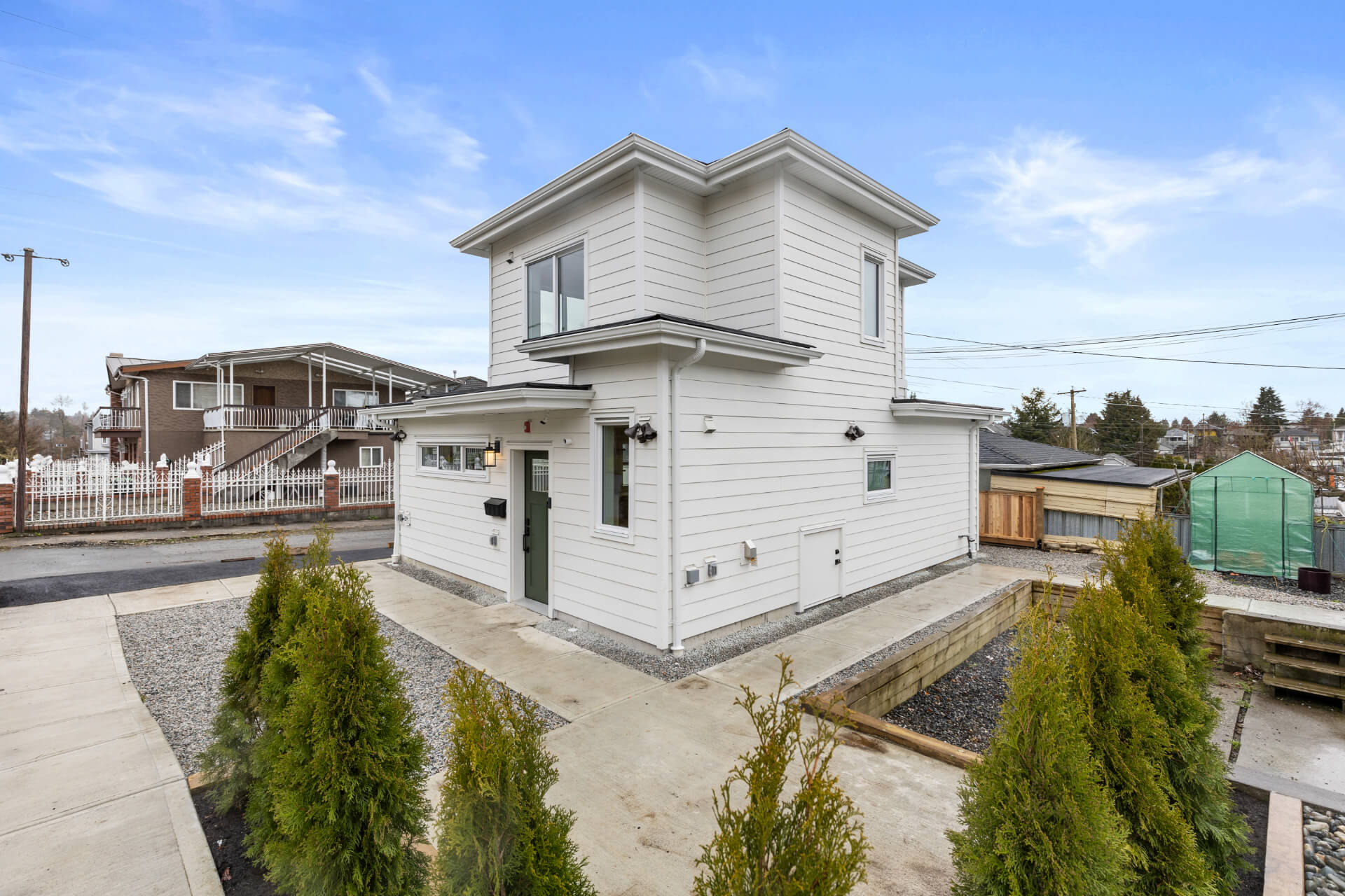 Photo of back side view of Lane way house with white siding and graveled back yard.