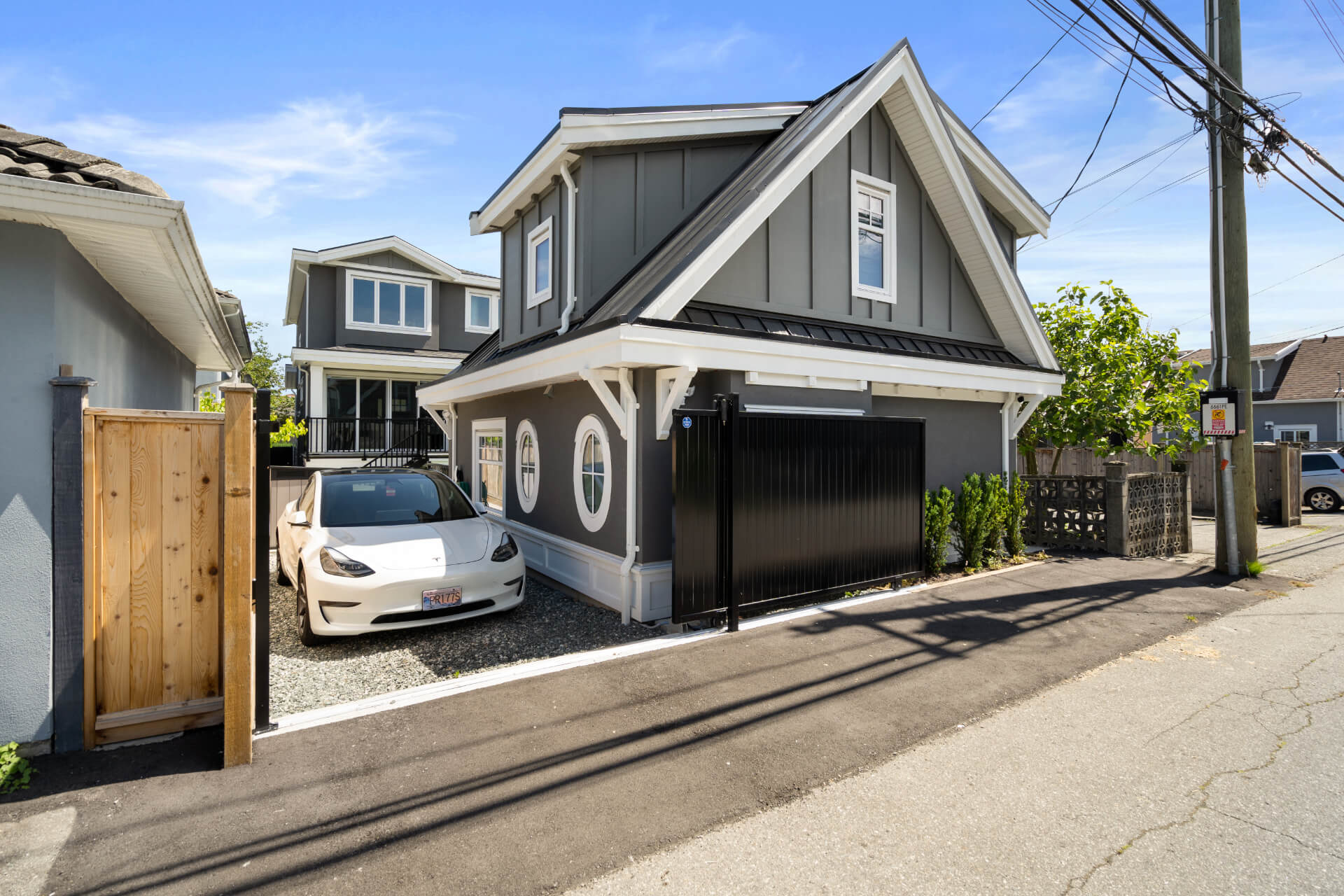 Sideview of beautiful grey and white Lane way house with two round windows.